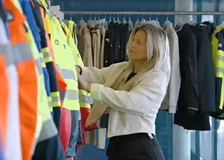 Vrouw gaat bij Scandia Gear door rek met werkkleding.
